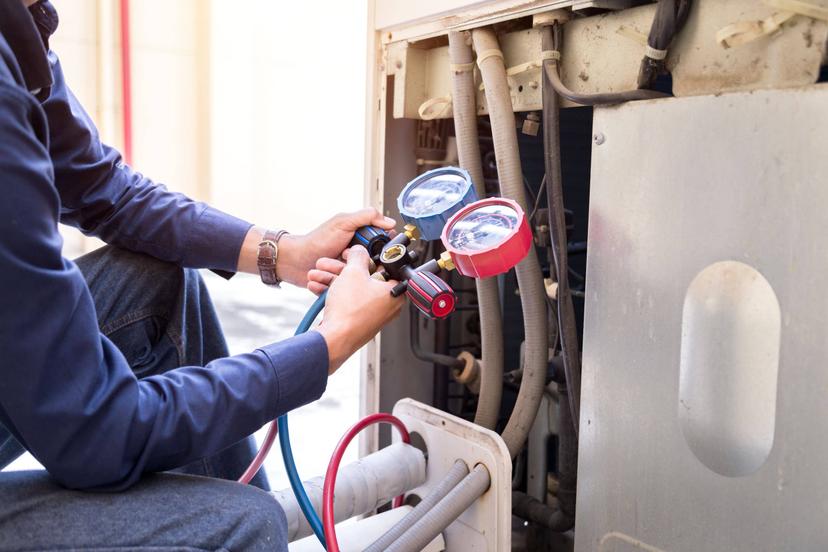 A man is working on an air conditioning unit.