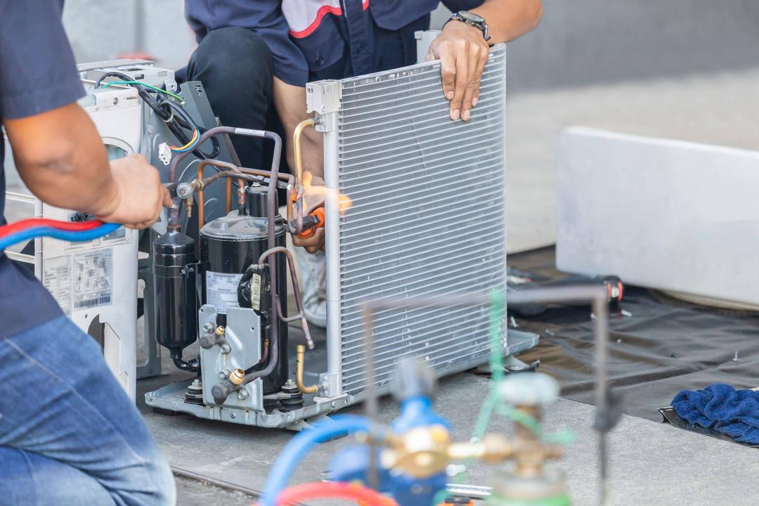 Two men working on an air conditioning unit.