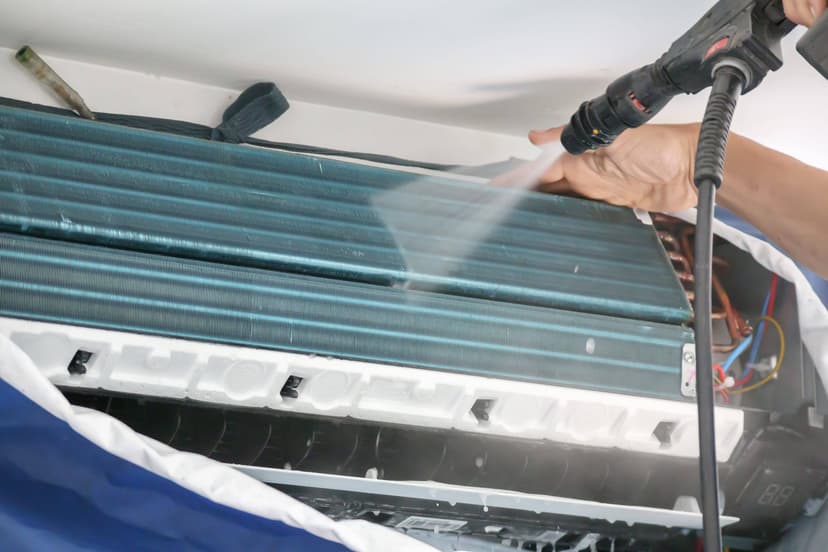 A person cleaning an air conditioning unit with a pressure washer, revealing internal components, serves as a perfect example of an HVAC unit coil.