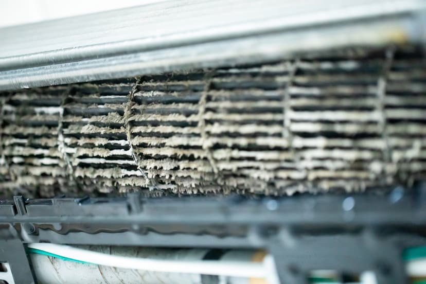 Close-up of a dirty and dusty air conditioner filter with accumulated debris, serving as an example of a neglected HVAC unit coil.