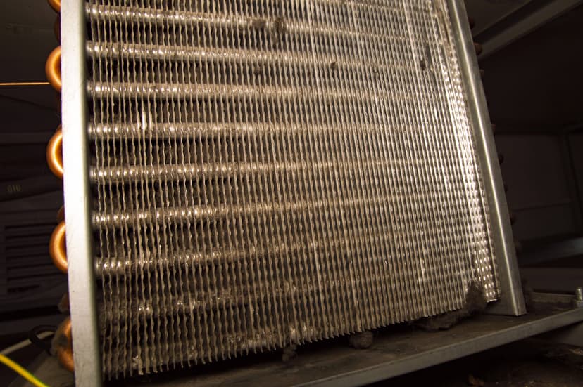 Close-up of a dust-covered metal air conditioning coil, an example of an HVAC unit coil, with visible dirt build-up between the fins.