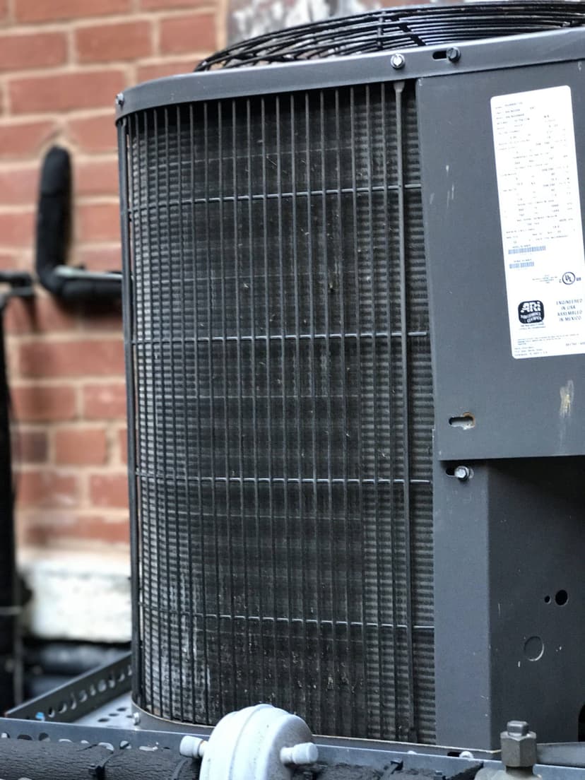 Close-up view of outdoor condensing units with a brick wall in the background.