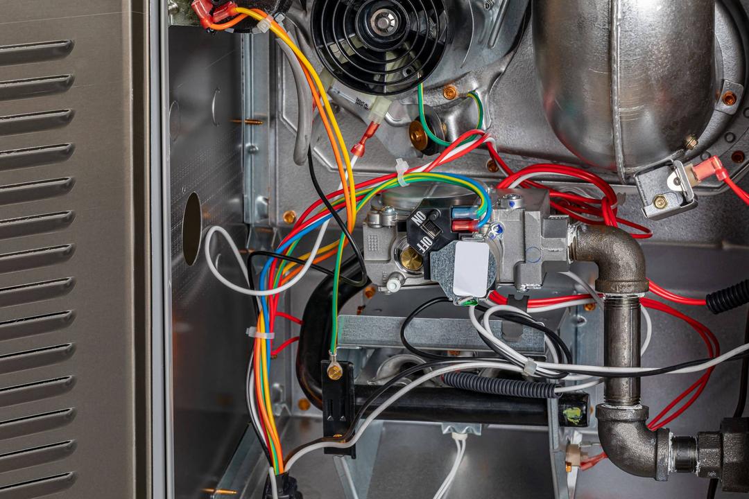 A close up of a gas furnace with wires and wires.