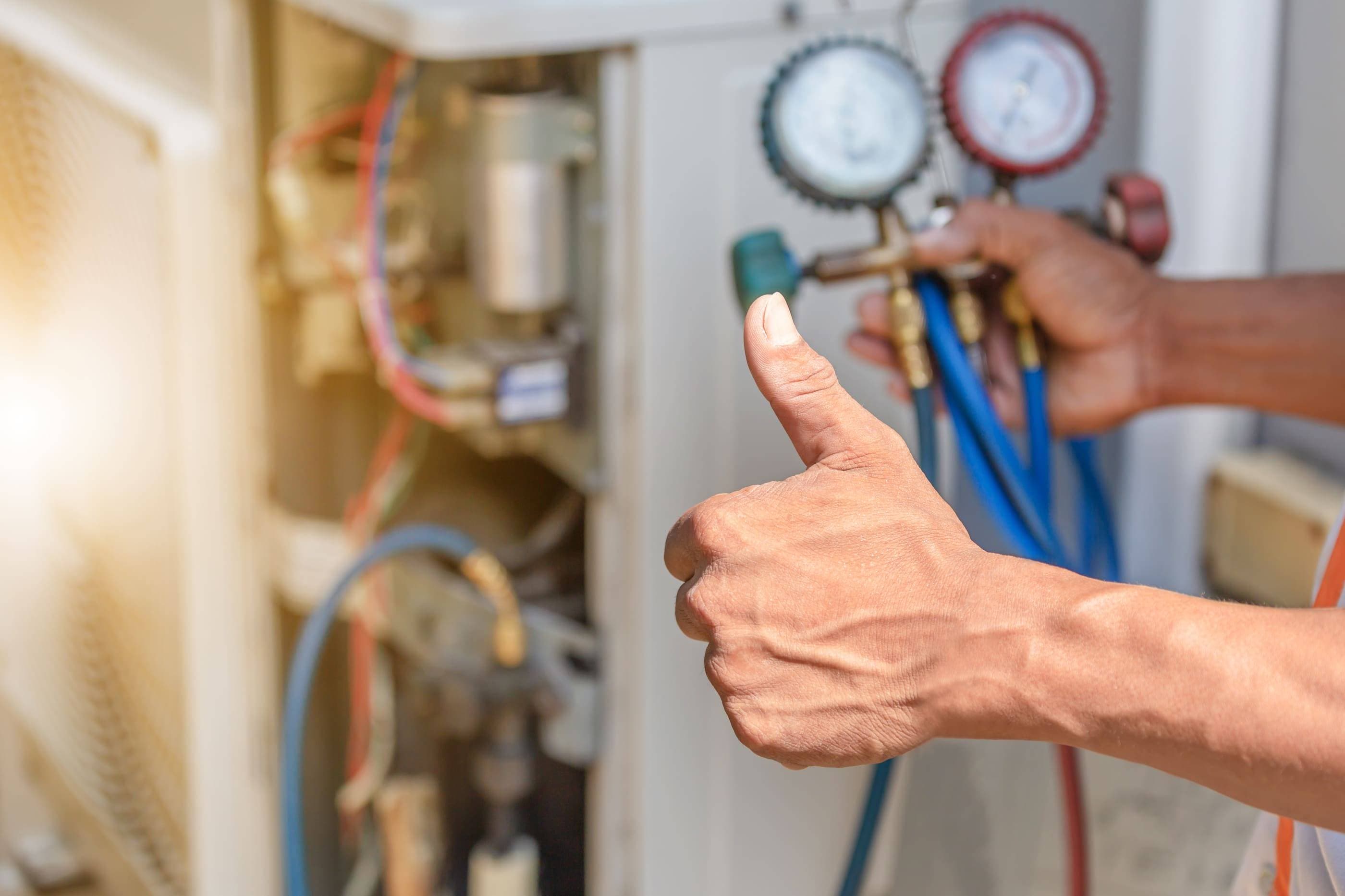 A man giving a thumbs up to an air conditioning unit.