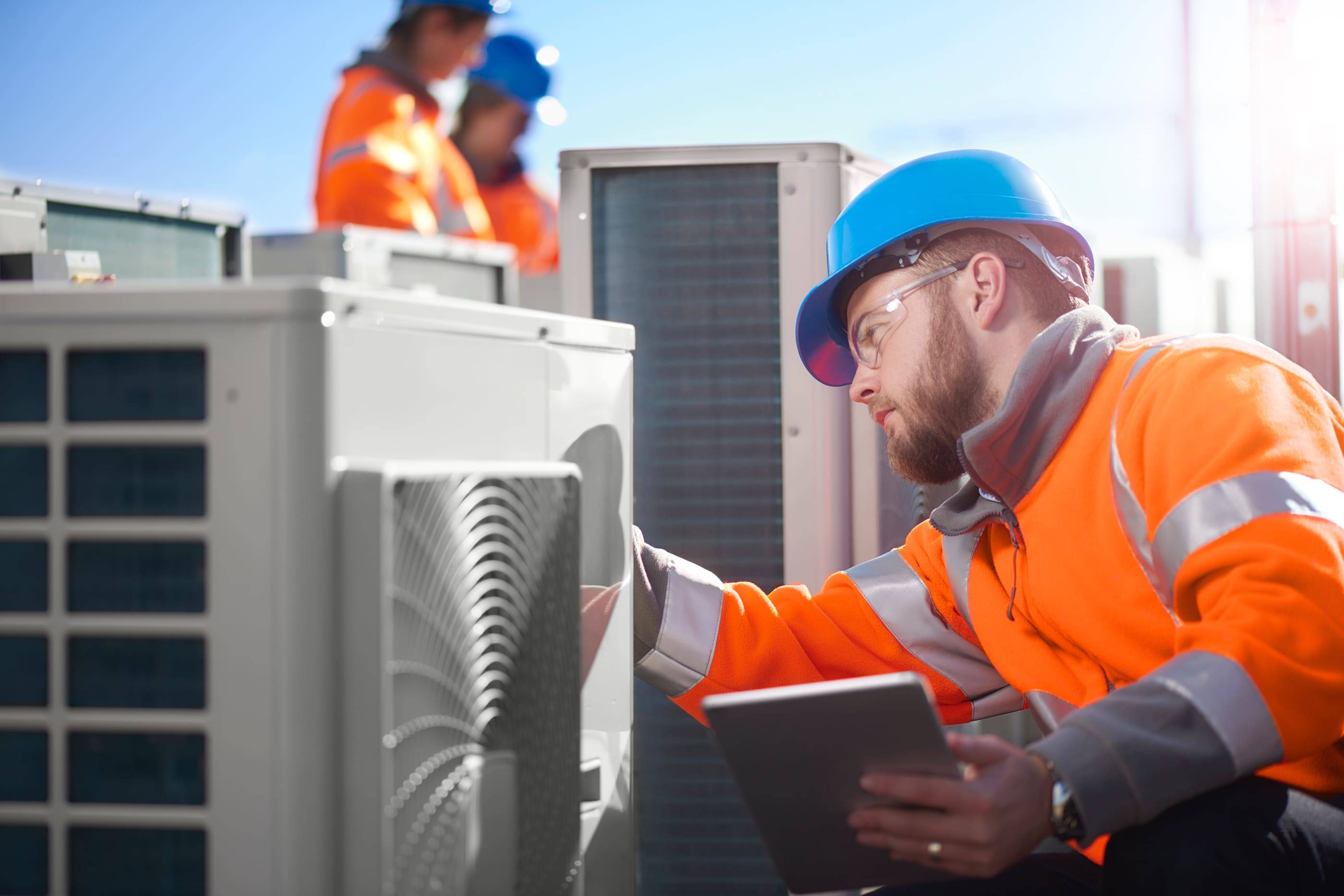 A construction worker inspecting an air conditioning unit.