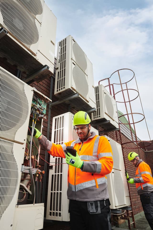 Two men working on an air conditioning unit.