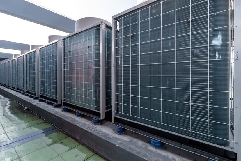 A row of large commercial HVAC systems lined up on a rooftop under a clear sky.