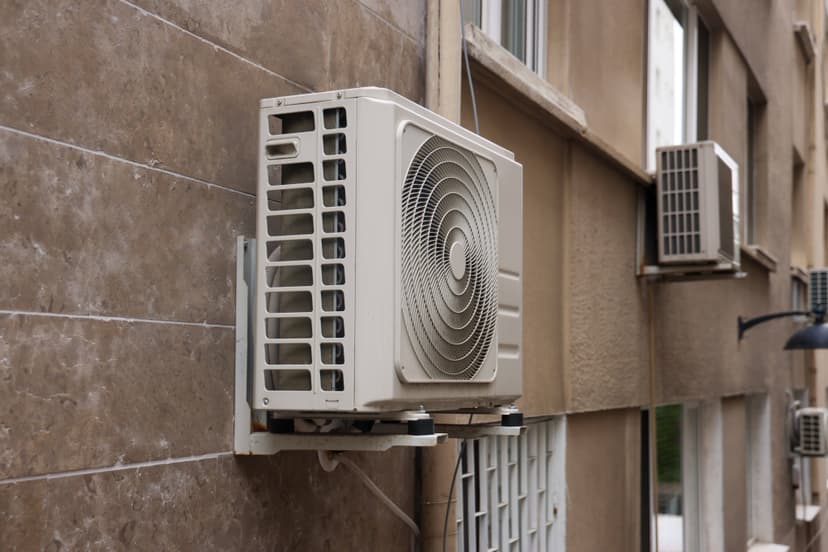 Commercial HVAC systems are mounted on the exterior wall of a beige building.