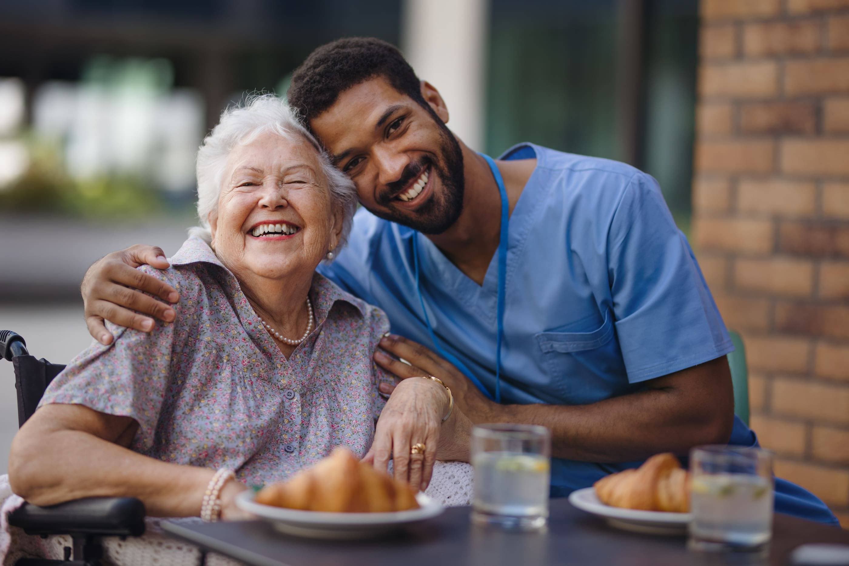 A nurse is hugging an elderly woman in a wheelchair.