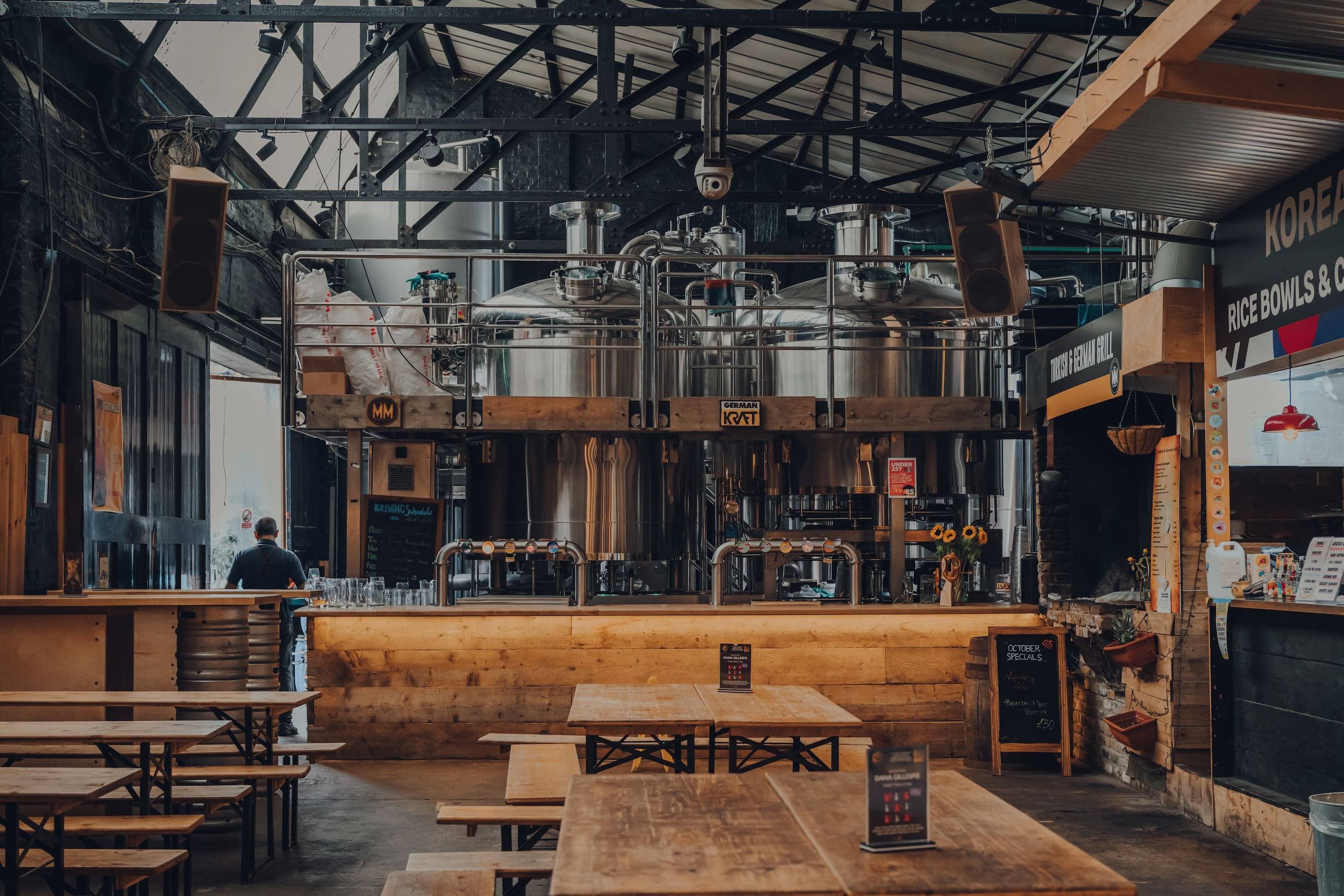 The inside of a brewery with tables and chairs.