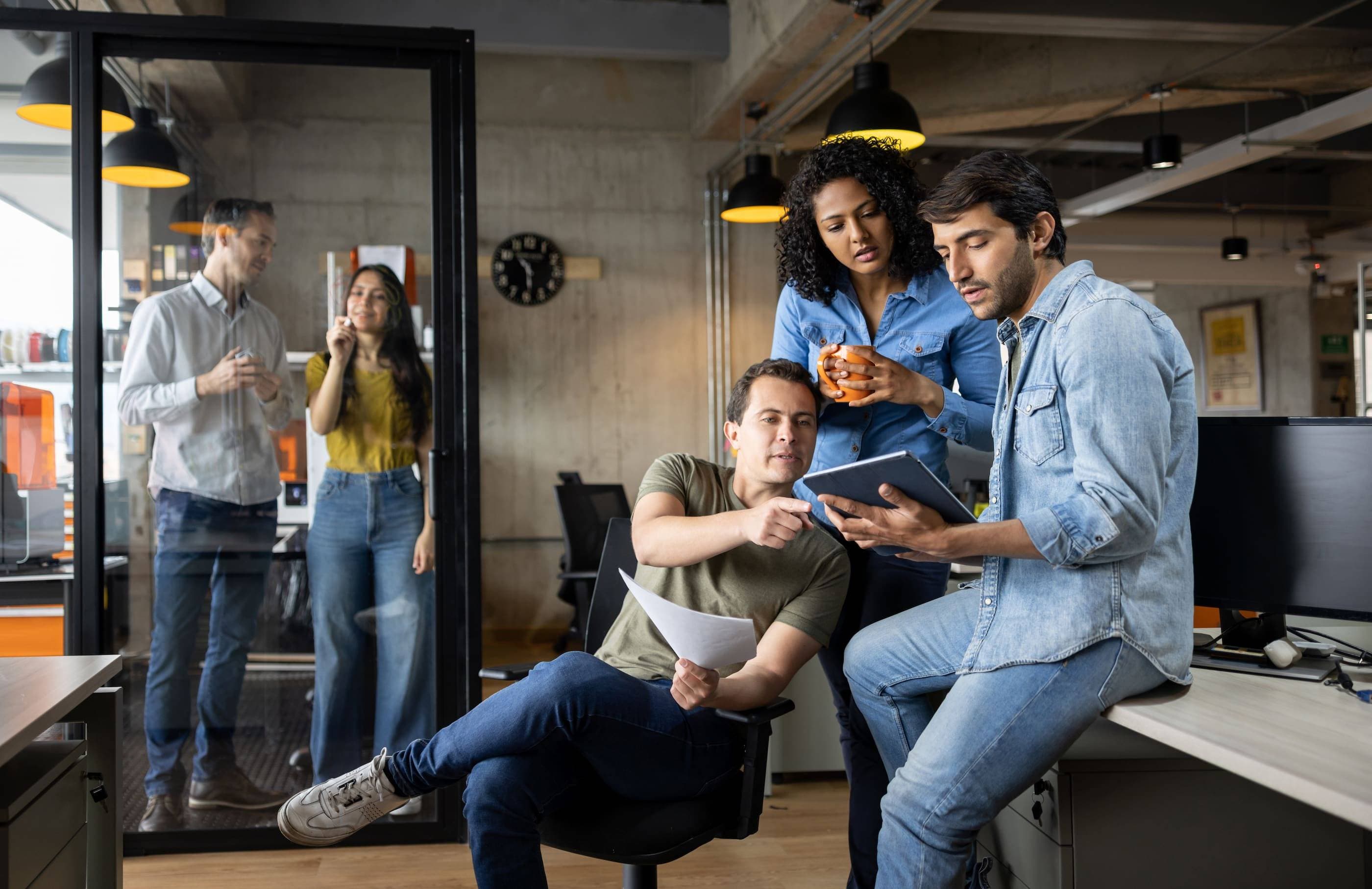 A group of people sitting at a desk in an office.