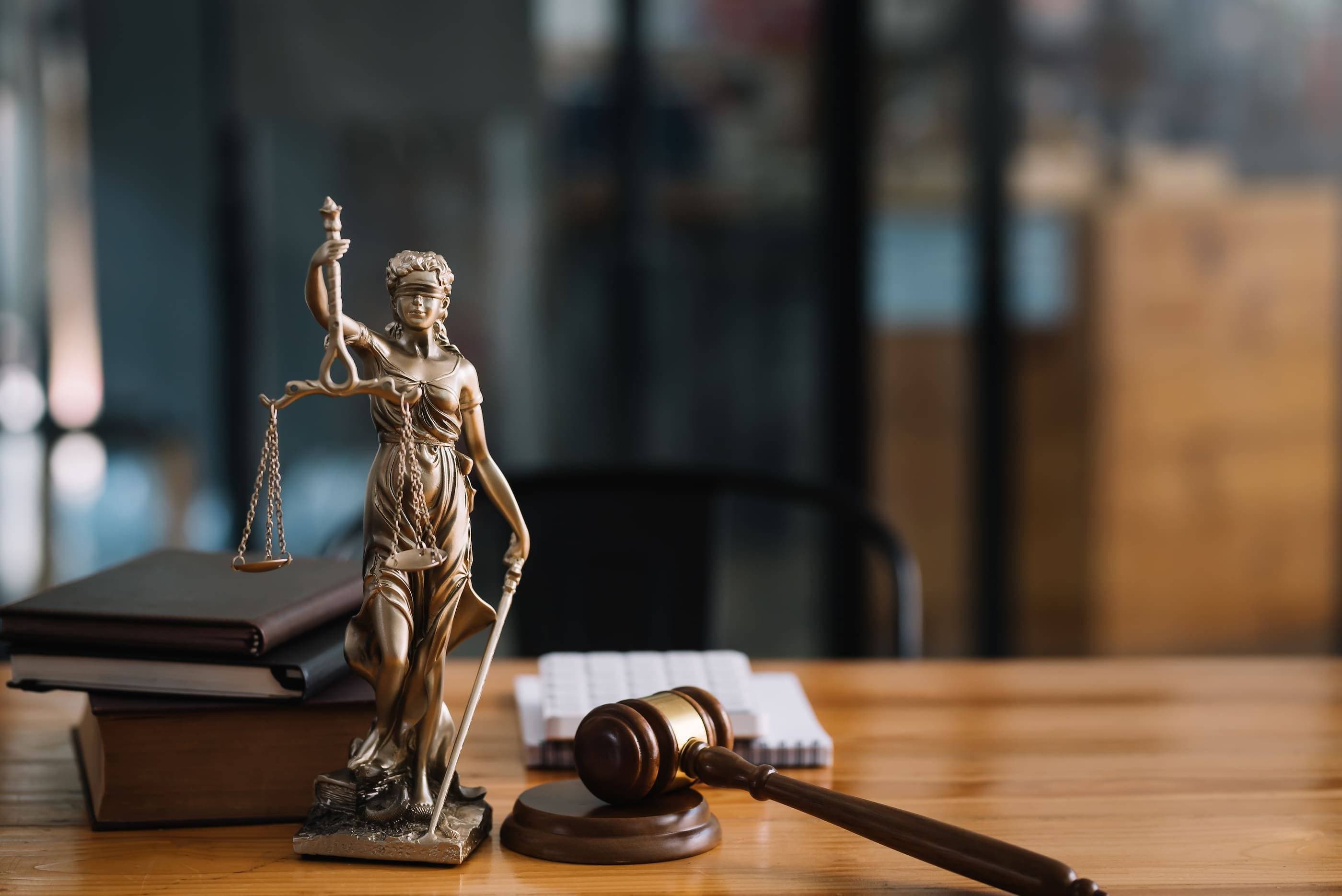 A statue of justice sitting on a table next to a book.