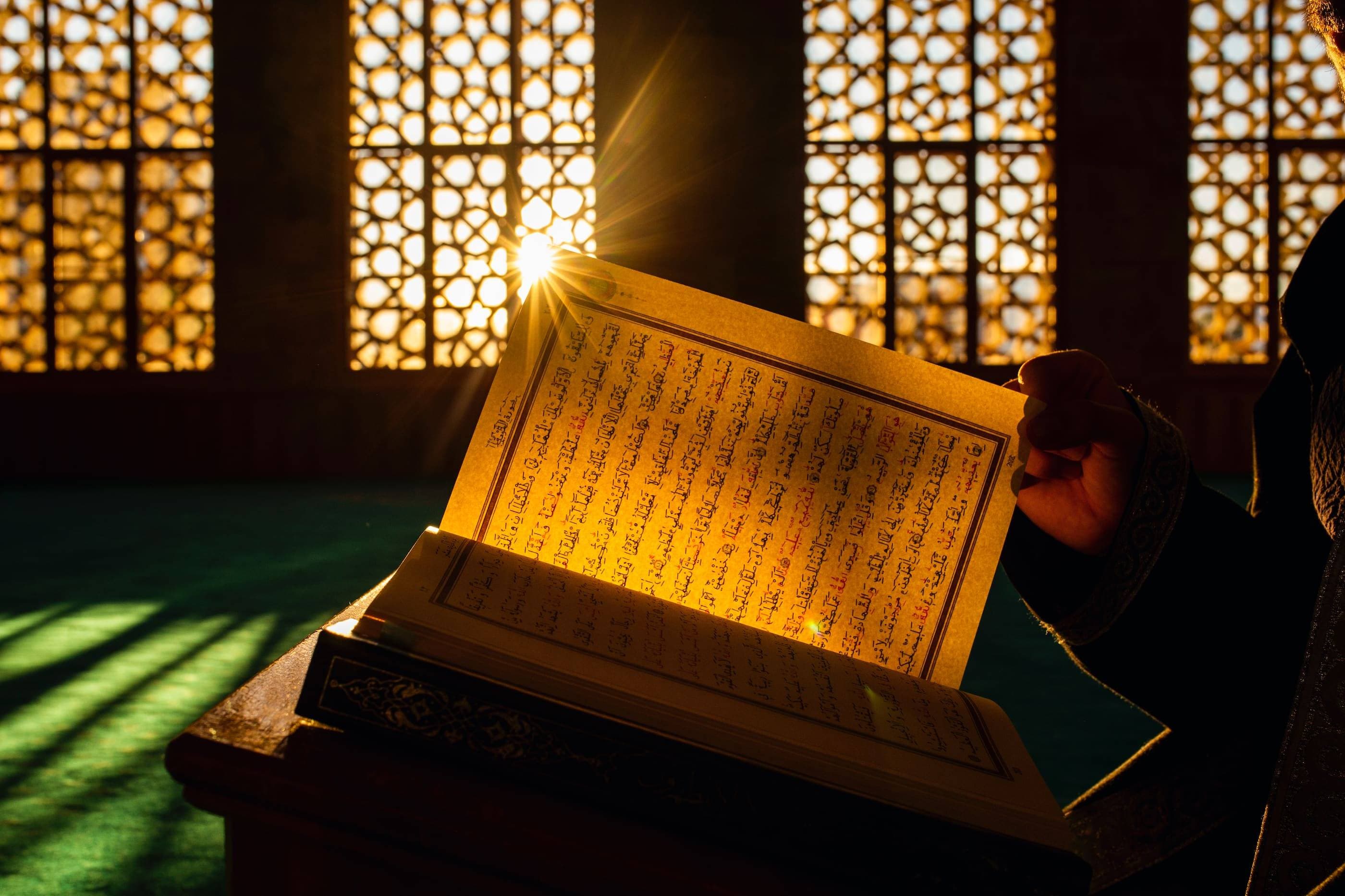 A man is reading the quran in front of a window.