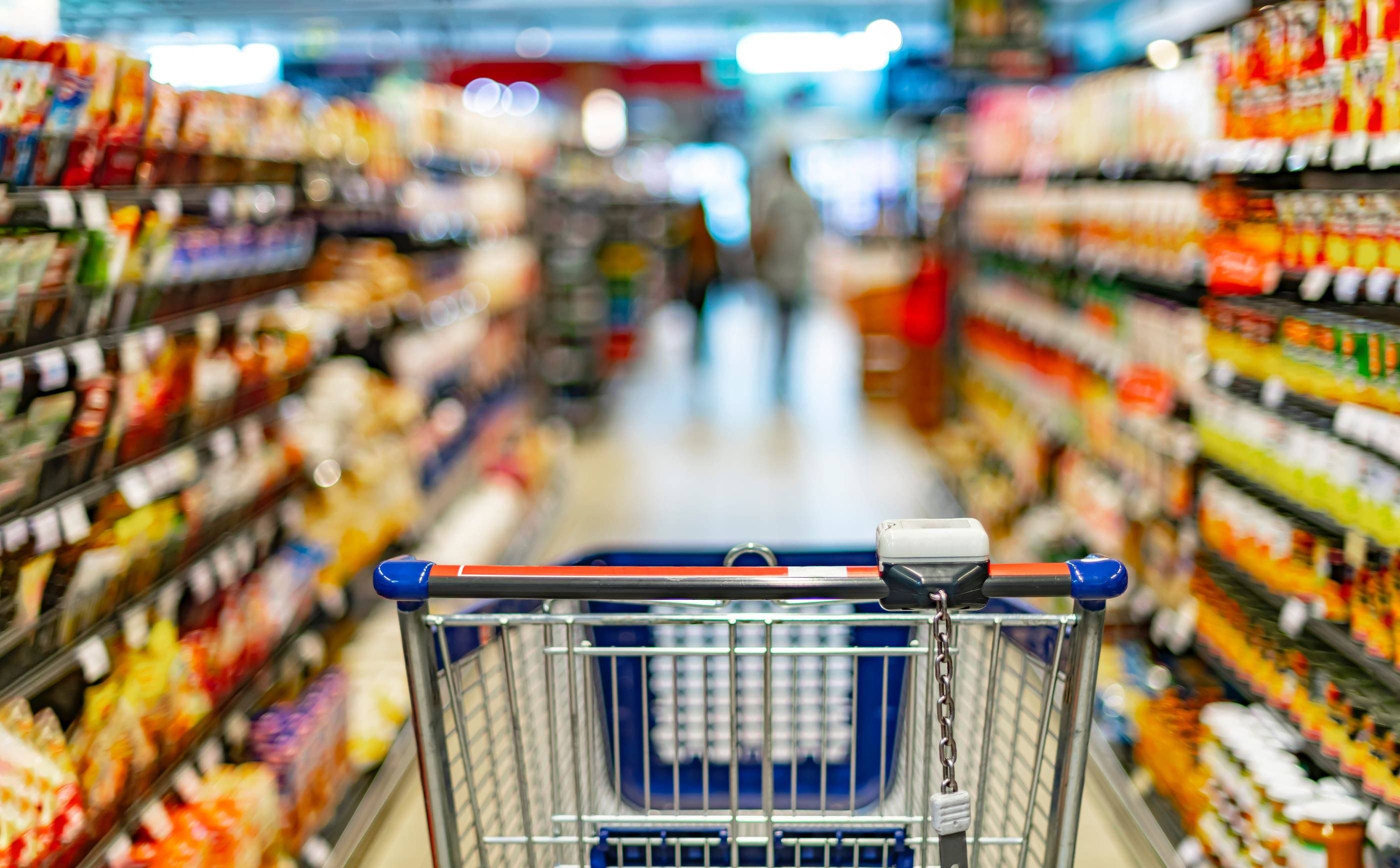 A shopping cart in a supermarket aisle.