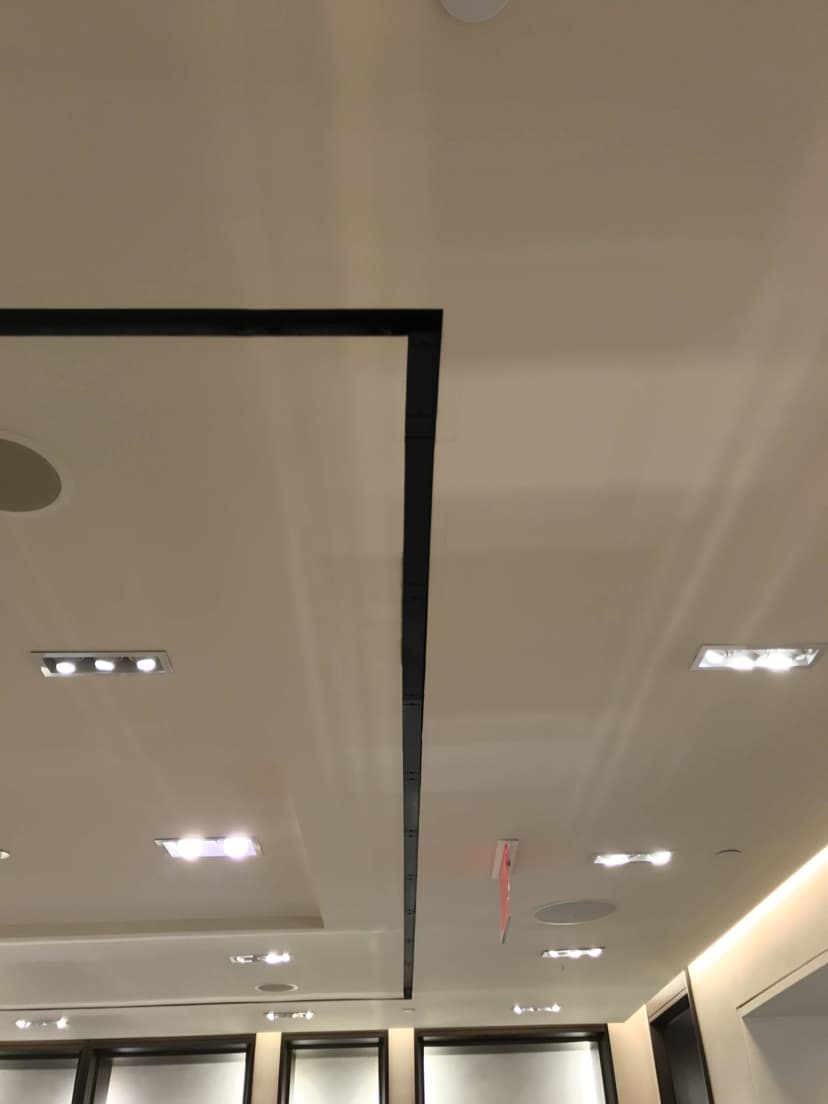 Ceiling with recessed lighting, circular speakers, black linear design elements, and state-of-the-art interior cooling. Walls adorned with framed artwork below.