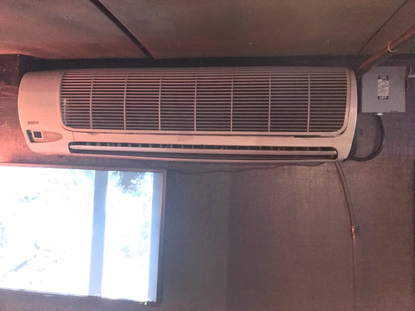 A wall-mounted air conditioner unit ensures interior cooling, installed in a dark room above a small window.