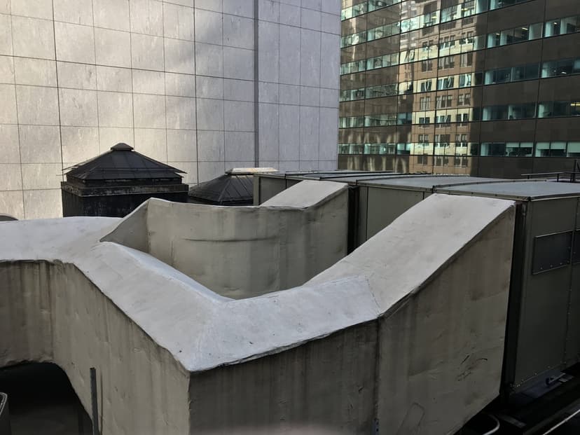 Rooftop view of urban buildings with commercial HVAC outdoor units and ventilation systems on a bright, clear day.