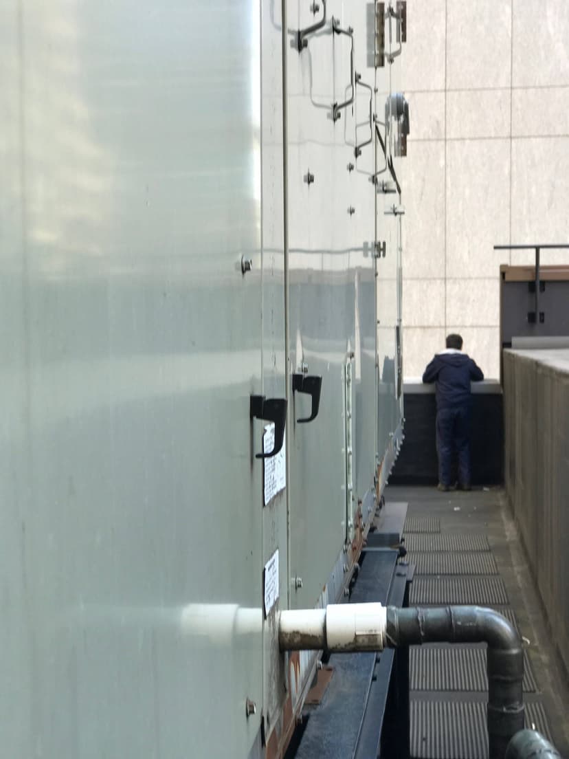 A person standing near commercial HVAC outdoor units on a rooftop.