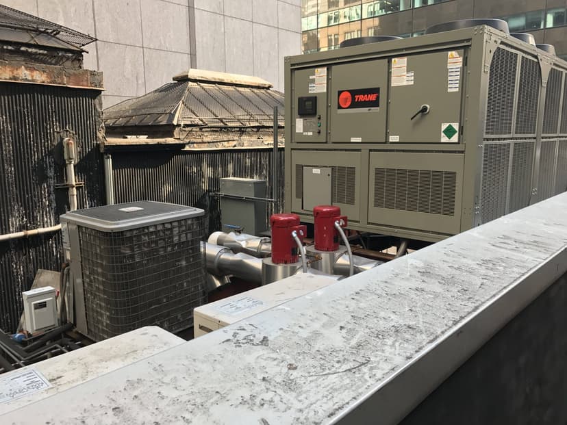 Rooftop view of multiple commercial HVAC outdoor units, including a large Trane unit and other smaller air conditioning equipment.