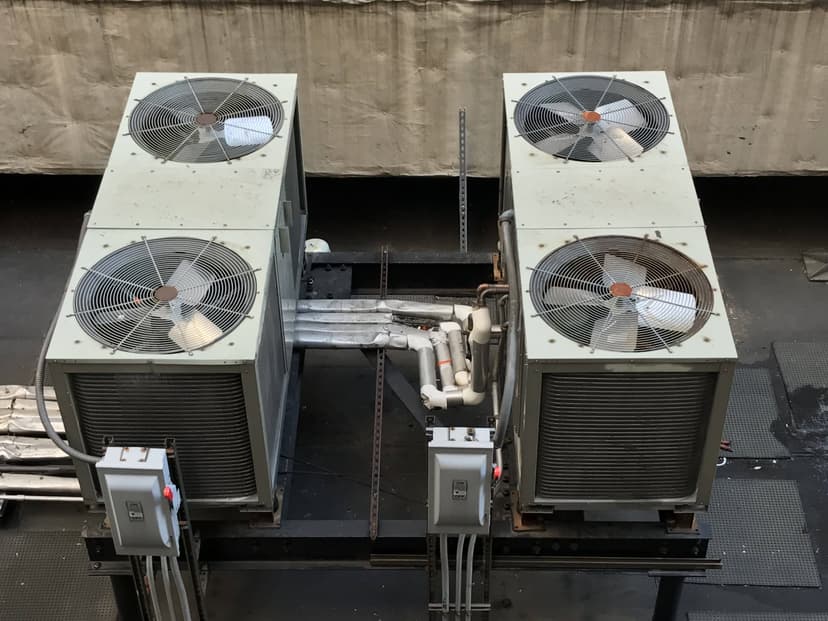 Two large commercial HVAC outdoor units are mounted on a platform in an industrial setting.