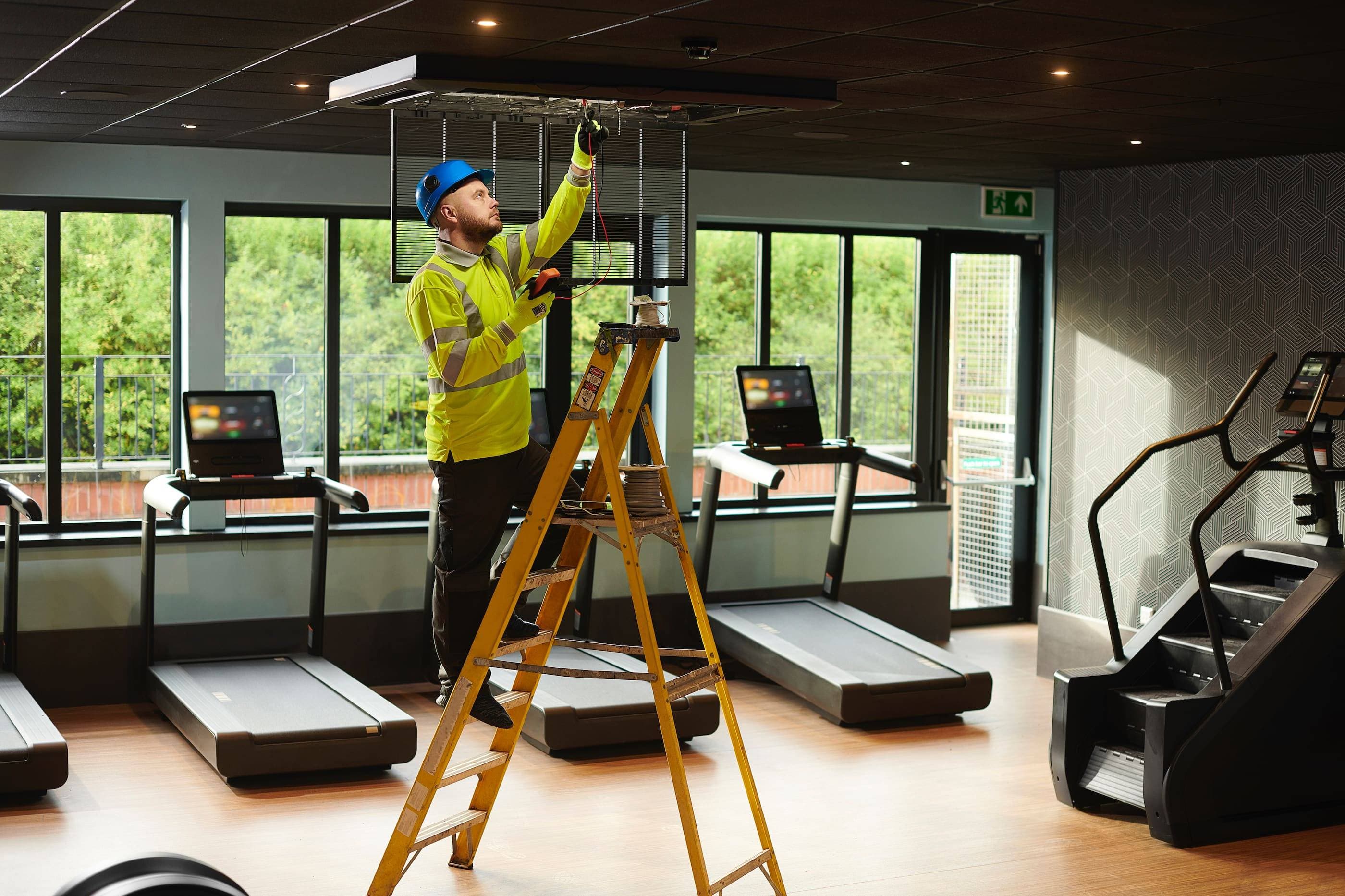 A man working on a ladder in a gym.