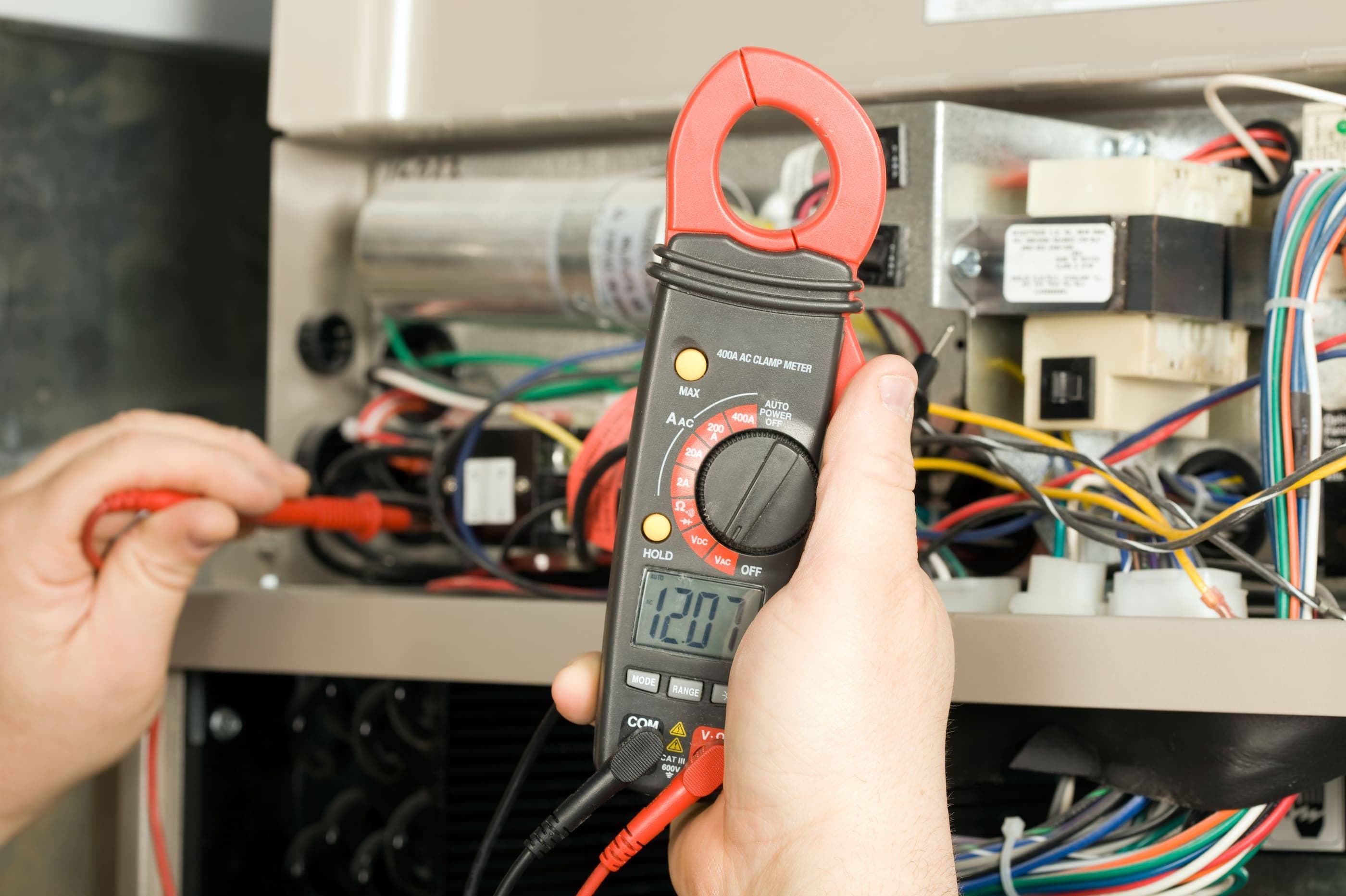 A person using a multimeter to check an air conditioner.