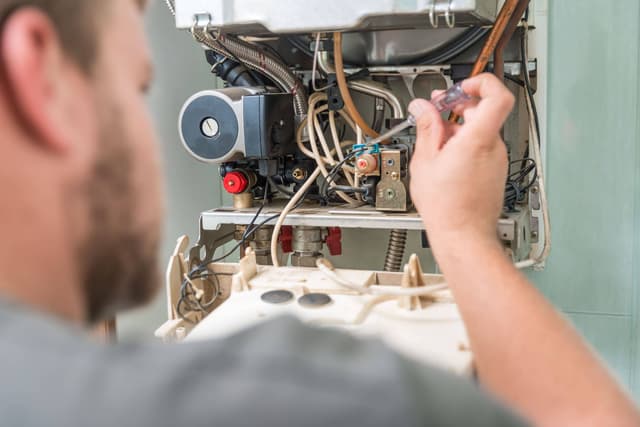 A man is working on a gas furnace.