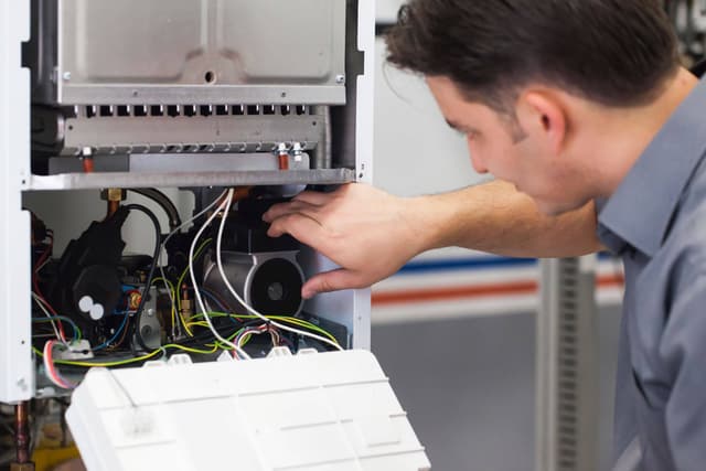 A man is working on a heating unit.