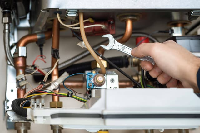 A man is working on a hot water heater.