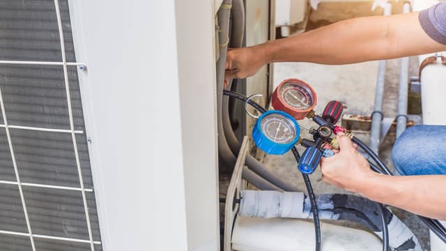 A man is working on an air conditioning unit.