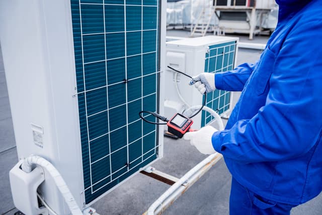 A technician is working on an air conditioning unit.