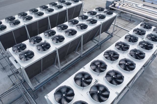 A row of industrial air conditioners on a roof.