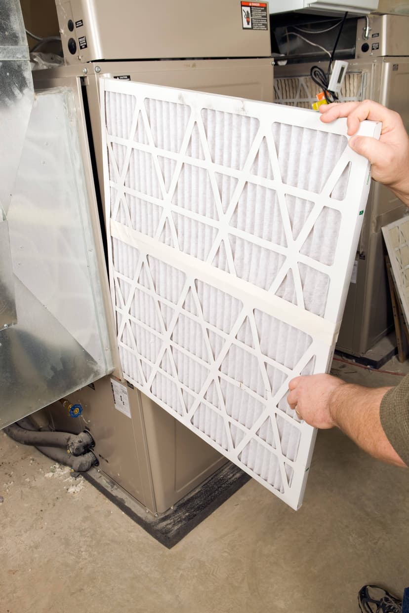 Person replacing an HVAC filter in a home furnace unit.